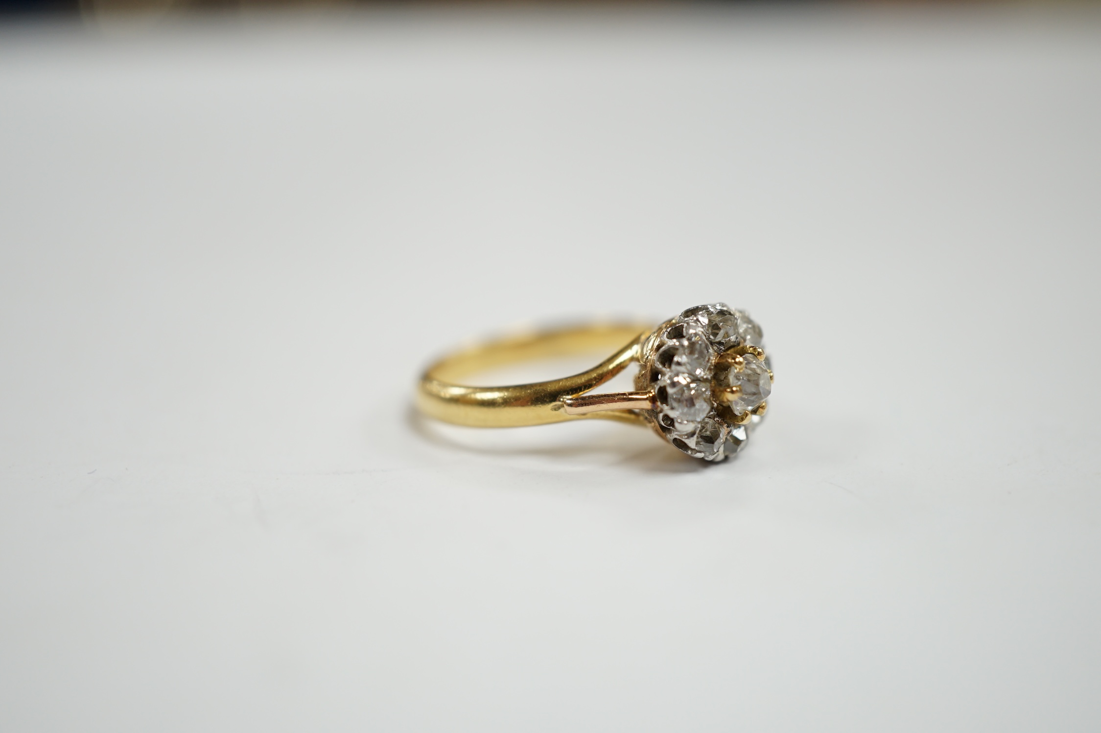 An early 20th century French 18k and nine stone diamond set flower head cluster ring, size G, gross weight 3.4 grams.
